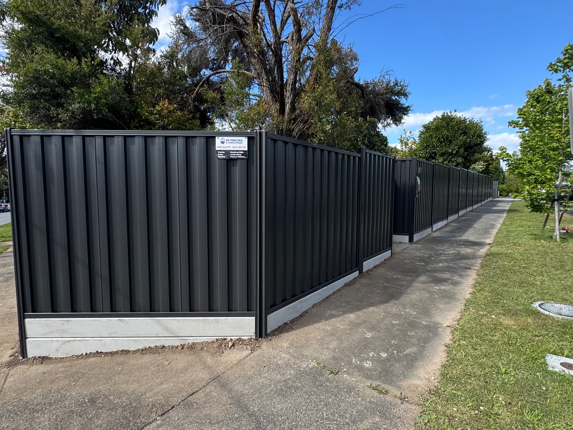 Long charcoal Colorbond fence line along a footpath